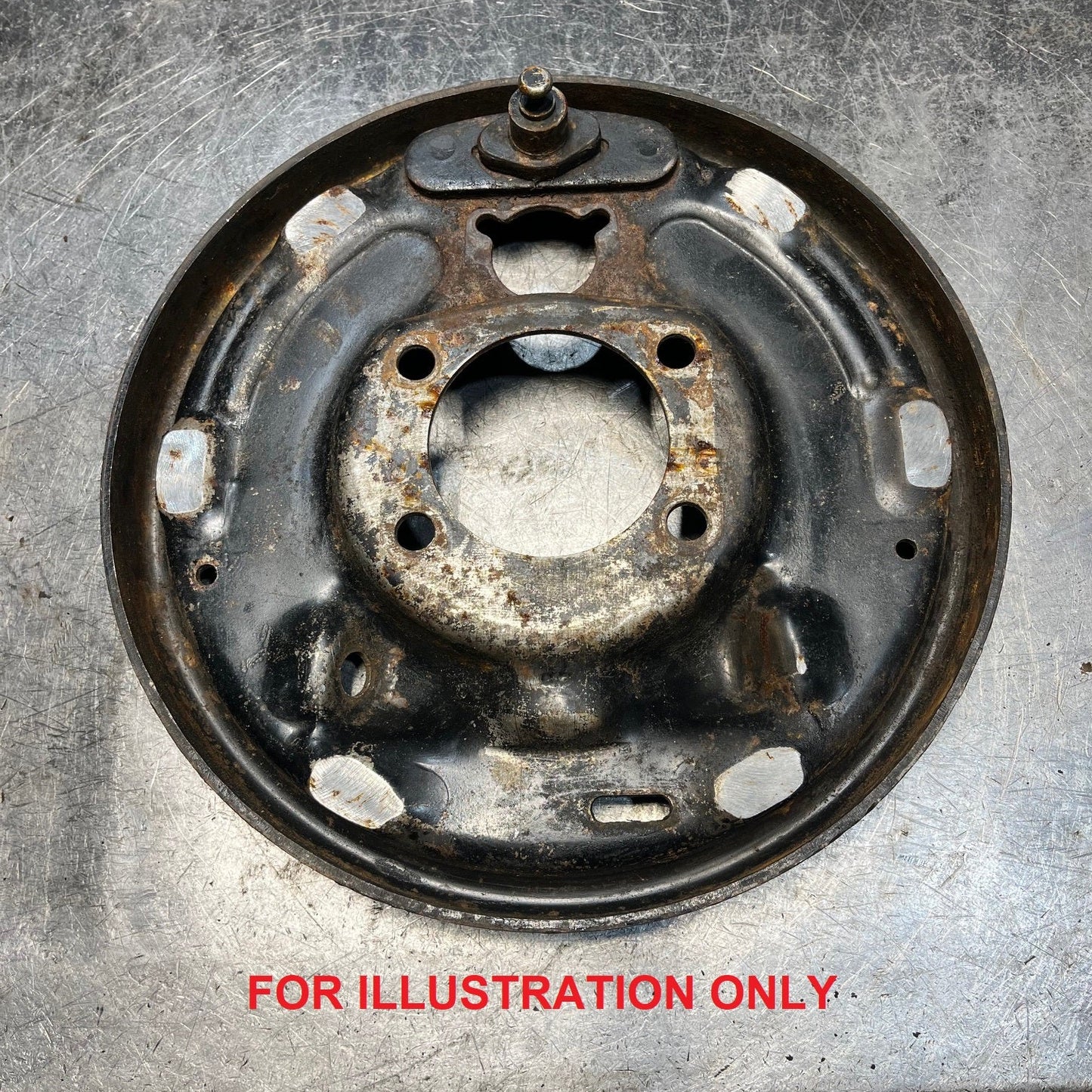 Used rear drum brake backing plate with mounting holes, side view