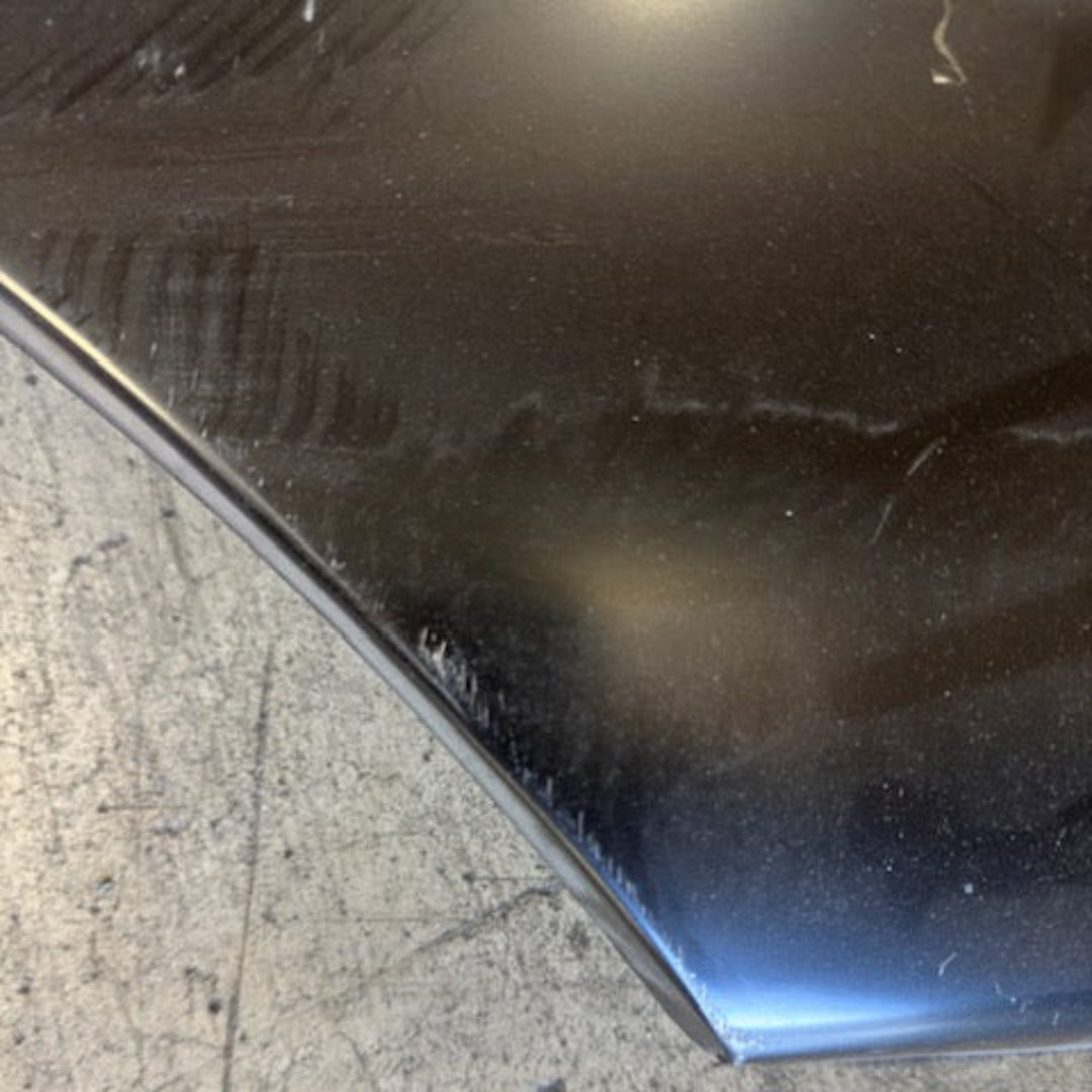Driver side lower quarter panel with visible dent, metal surface