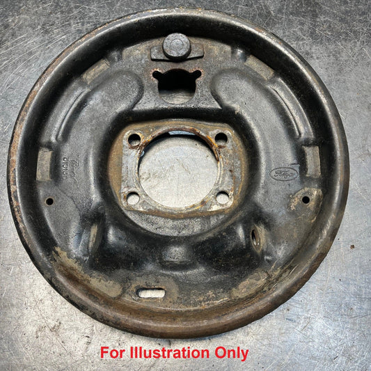 Used rear drum brake backing plate with rust and wear marks, side view